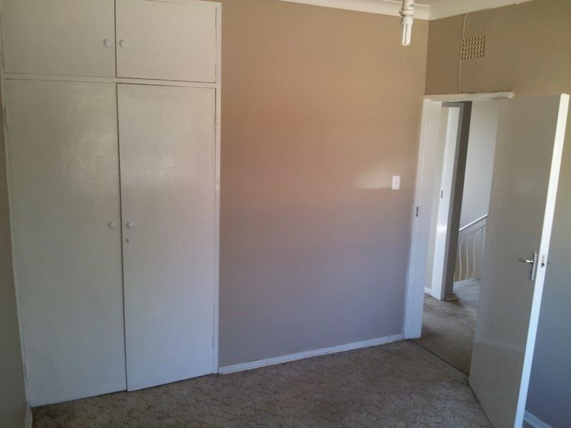 An empty bedroom featuring built-in cupboards, carpeted flooring, and neutral wall tones, offering a blank canvas for potential updates.