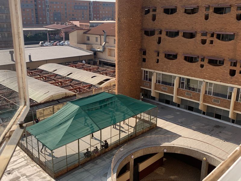 Elevated view overlooking a residential complex courtyard featuring a sunken circular area, brick architecture, and a shaded outdoor sports facility.