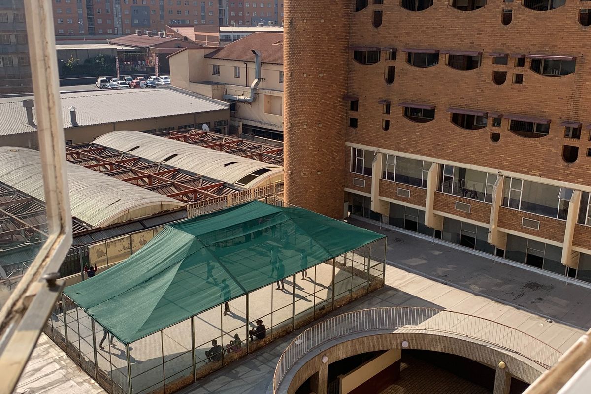 Elevated view overlooking a residential complex courtyard featuring a sunken circular area, brick architecture, and a shaded outdoor sports facility.