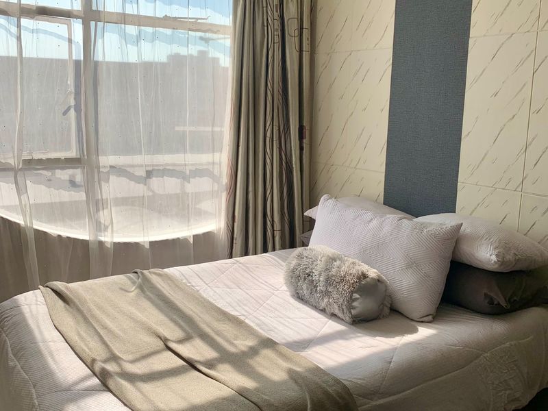 A bedroom featuring a large window with natural light and a decorative tiled accent wall.