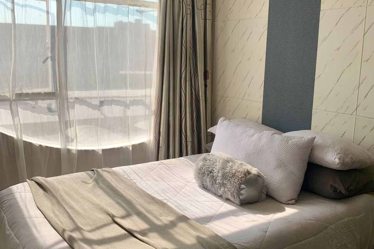 A bedroom featuring a large window with natural light and a decorative tiled accent wall.