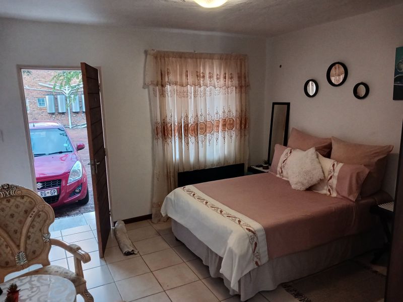 A bedroom featuring tiled flooring and direct access to the exterior parking area.