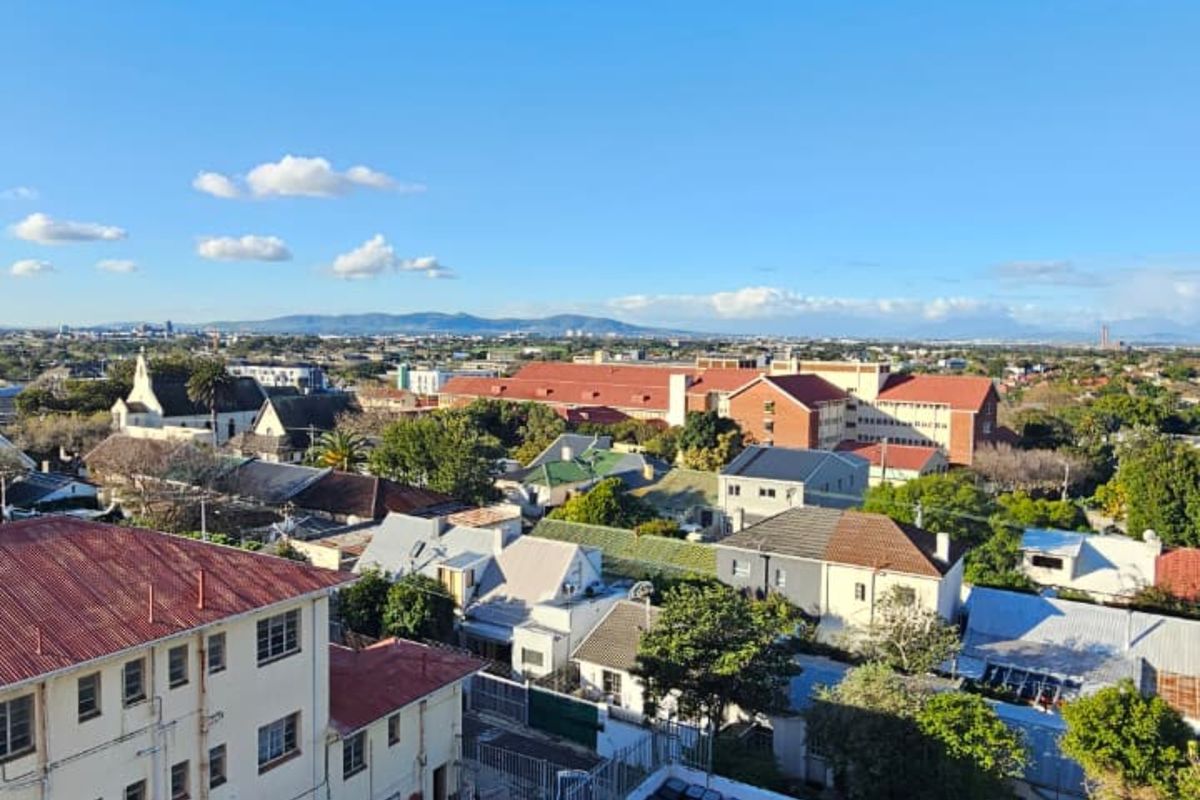 Elevated aerial view overlooking the surrounding residential neighborhood, parking area, and distant mountain landscape.