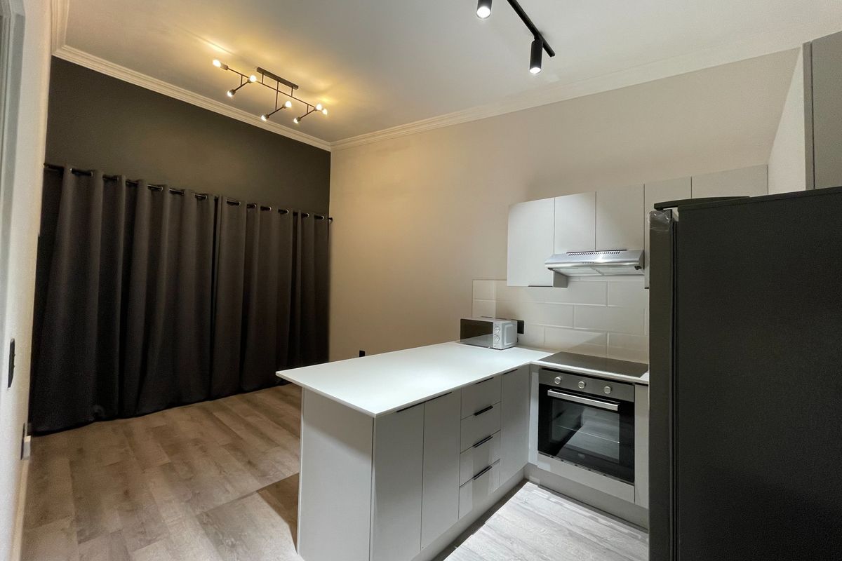 Modern open-plan kitchen and living area featuring sleek cabinetry, built-in appliances, subway tile backsplash, and contemporary track lighting.