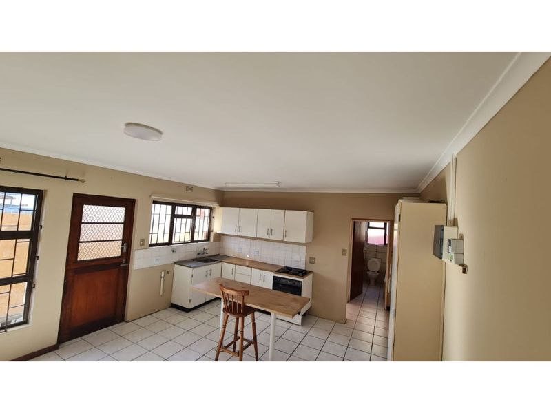 Open plan kitchen area featuring tiled flooring, built-in cabinetry, and integrated stove, with direct access to an adjacent bathroom and exterior door.