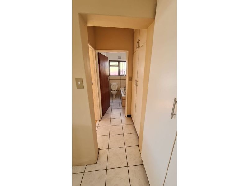 A functional hallway featuring tiled flooring and built-in storage cupboards, providing direct access to the adjacent bathroom.