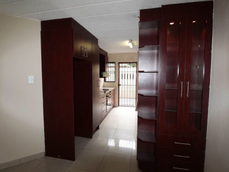 A functional kitchen featuring dark wood cabinetry, built-in oven and hob, tiled flooring, and direct access to an exterior security gate.