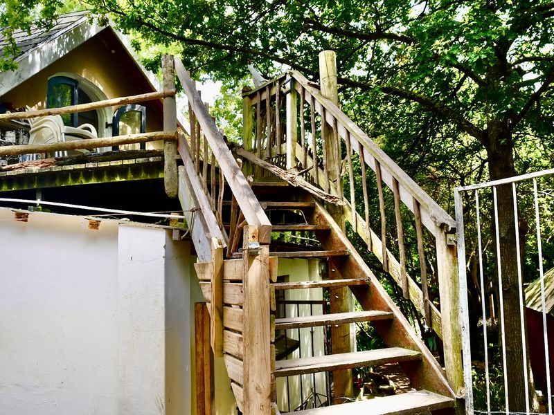 Exterior view of a rear property area featuring a weathered wooden staircase leading to an elevated deck with visible signs of wear.