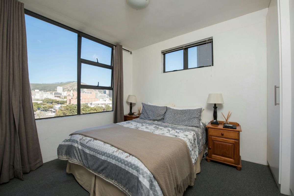 A bedroom featuring large windows with city views, built-in wardrobe, and carpeted flooring.