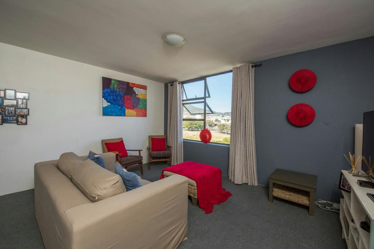 A comfortable living room featuring grey carpeting, a feature wall, and a large window providing natural light and scenic views.