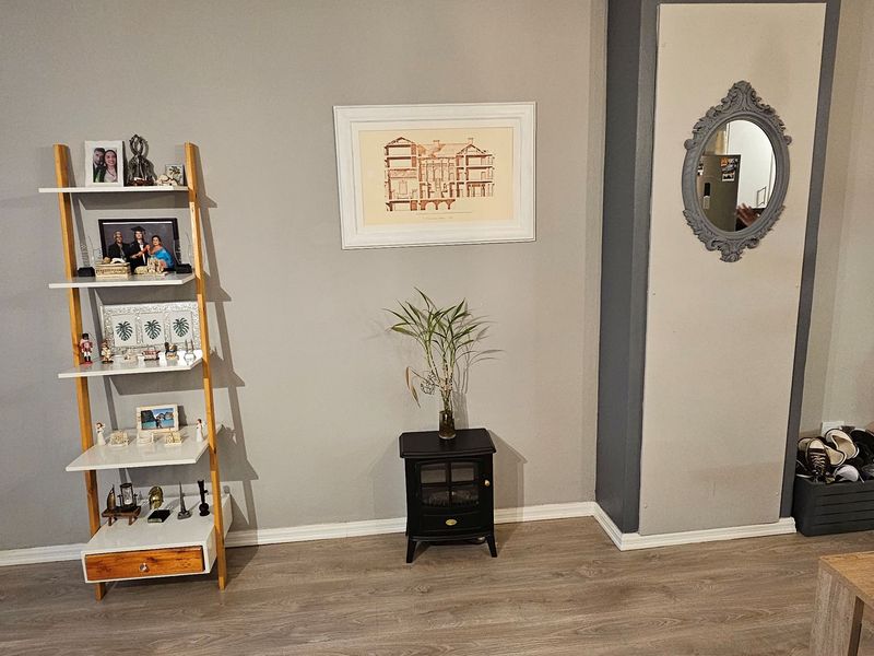 A living room area featuring wood-look laminate flooring and a neutral painted feature wall with a built-in chimney breast detail.
