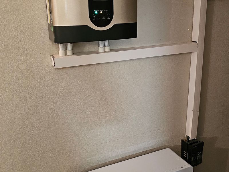 A wall-mounted Fivestar hybrid solar inverter paired with a Sun God LiFePO4 battery and electrical distribution board, representing a modern off-grid power solution.
