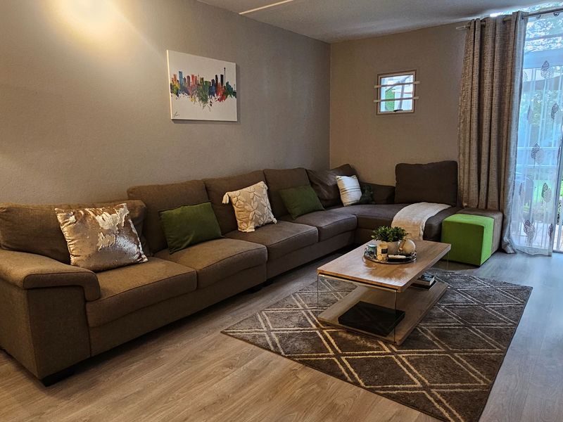 A comfortable living room featuring light-toned laminate flooring and a sliding glass door that provides access to the outdoor area.
