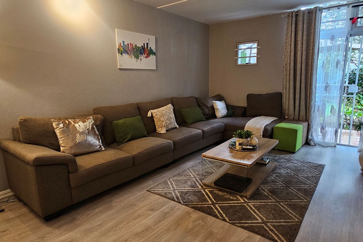 A comfortable living room featuring light-toned laminate flooring and a sliding glass door that provides access to the outdoor area.