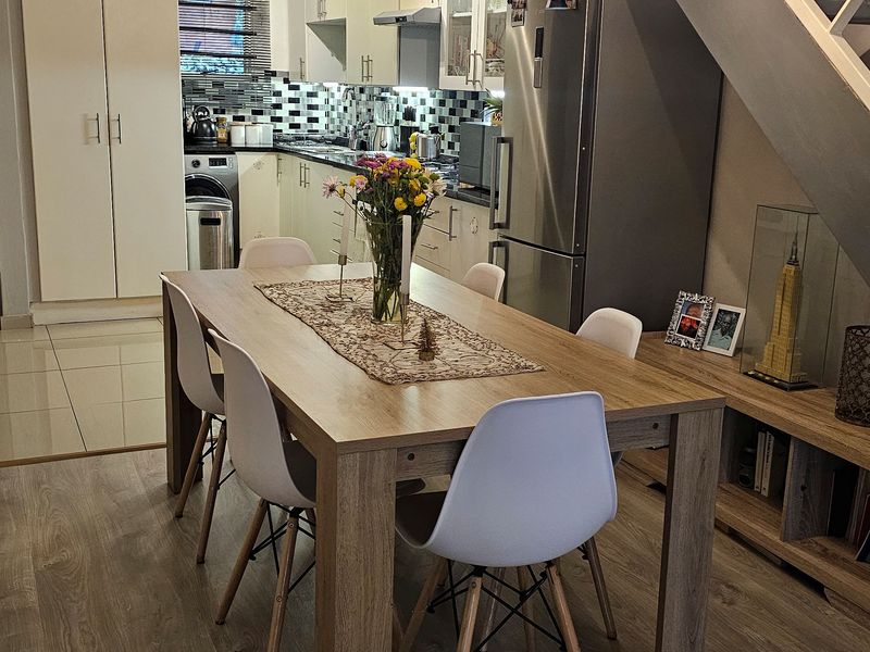 Open plan living and dining area featuring modern laminate flooring, a functional kitchen with built-in cabinetry, and a staircase leading to the upper level.