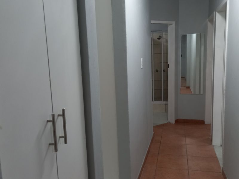 A functional hallway featuring tiled flooring and built-in storage cupboards, providing access to adjacent rooms including a bathroom.