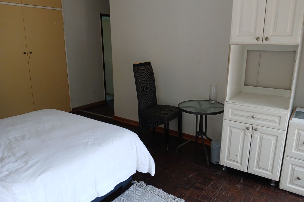 A bedroom featuring parquet flooring and built-in cupboards, offering a functional space with potential for cosmetic updates to improve the overall aesthetic.
