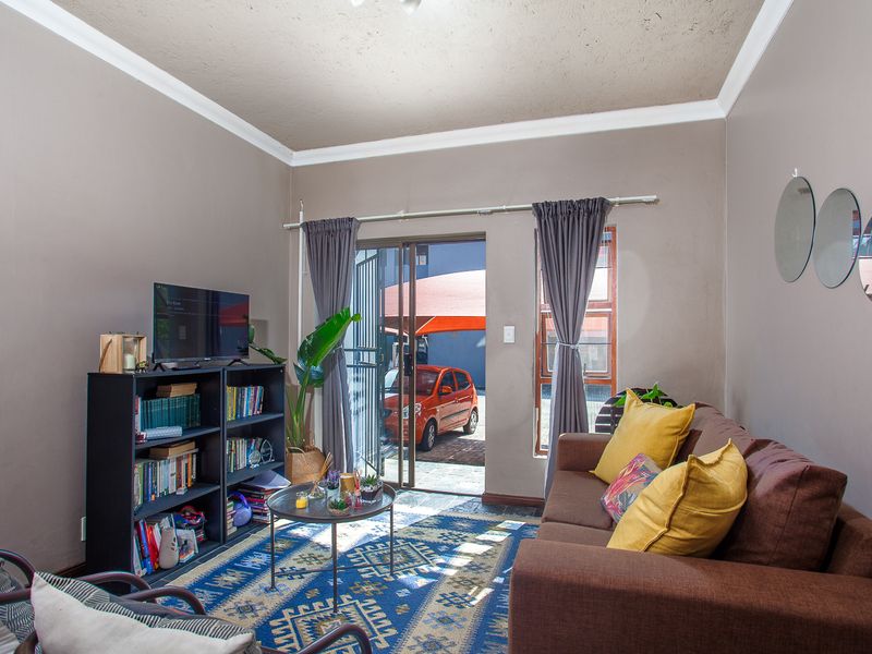A cozy living room featuring a sliding glass door with security gate, providing direct access to the exterior parking area.