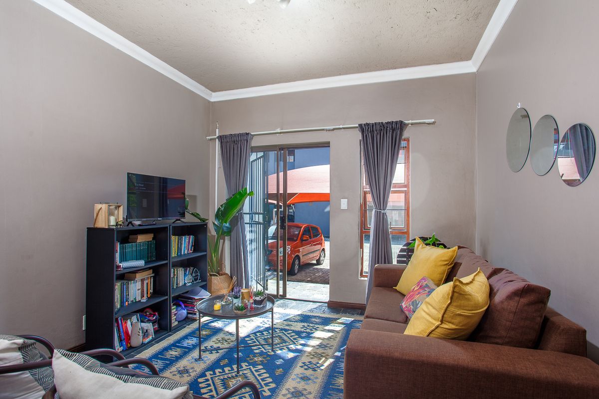 A cozy living room featuring a sliding glass door with security gate, providing direct access to the exterior parking area.