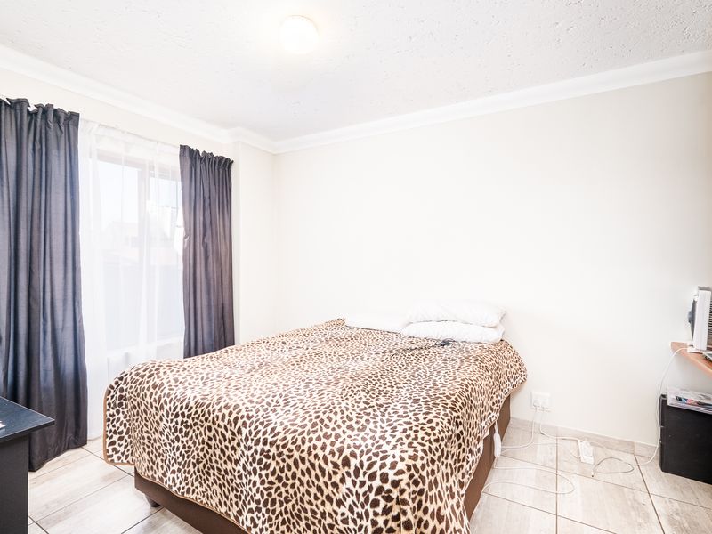 A bedroom featuring tiled flooring, a built-in wardrobe, and a window with curtain tracks.