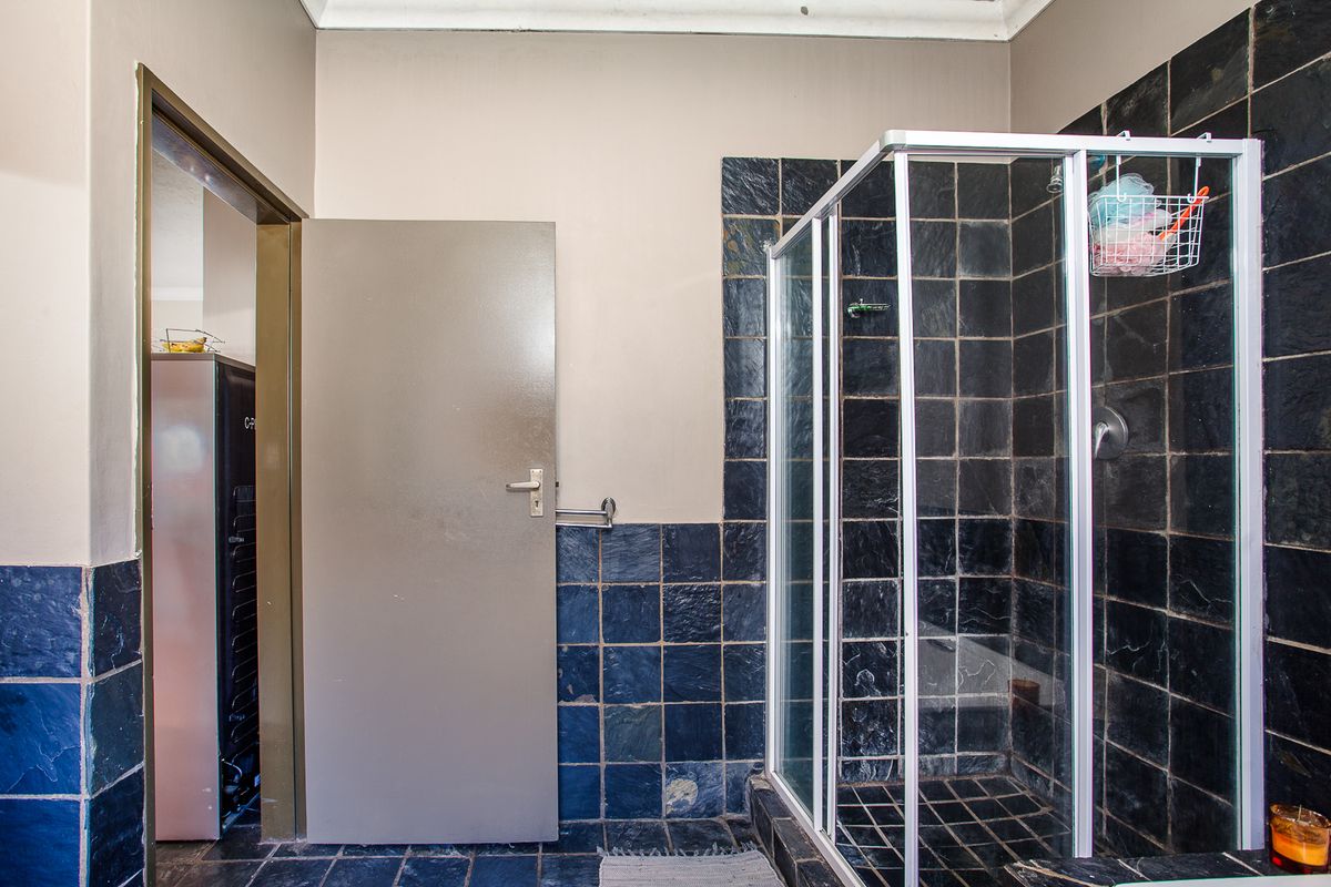 A functional bathroom featuring a glass shower enclosure and dark slate wall and floor tiling.