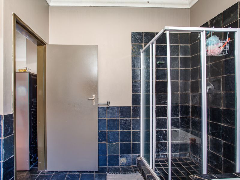 A functional bathroom featuring a glass shower enclosure and dark slate wall and floor tiling.