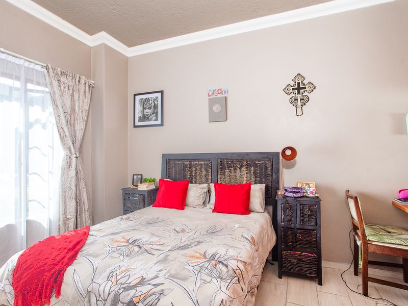 A well-lit bedroom featuring tiled flooring, crown molding, and a sliding glass door providing natural light.