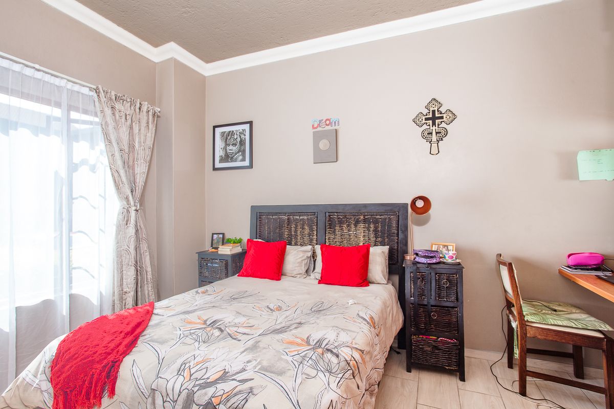 A well-lit bedroom featuring tiled flooring, crown molding, and a sliding glass door providing natural light.