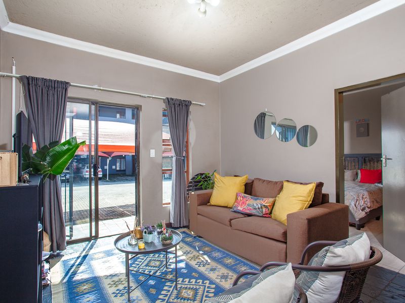 A comfortable living room featuring tiled flooring, a sliding glass door providing natural light, and direct access to an adjacent bedroom.