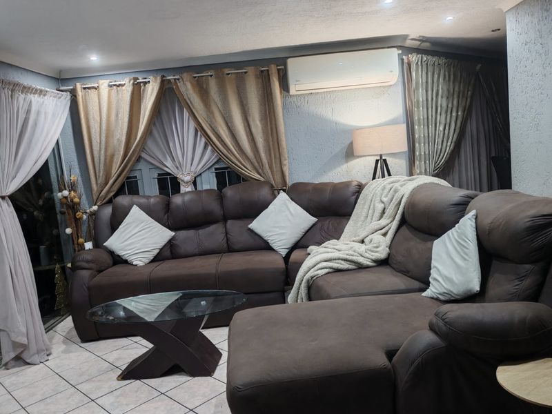A comfortable living room featuring tiled flooring, textured walls, recessed downlighting, and a wall-mounted split-system air conditioning unit.