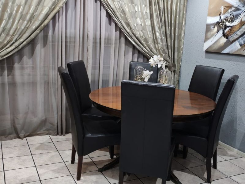 A dining area featuring tiled flooring and floor-to-ceiling curtains, providing a functional space for meals.