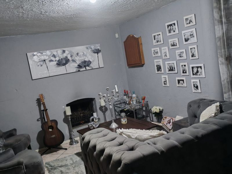 A living room featuring a built-in fireplace and tiled flooring, currently finished with grey wall paint and a textured ceiling.