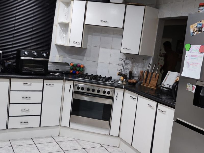 A functional kitchen featuring white built-in cabinetry, a gas hob, an integrated oven, and tiled flooring with a tiled backsplash.