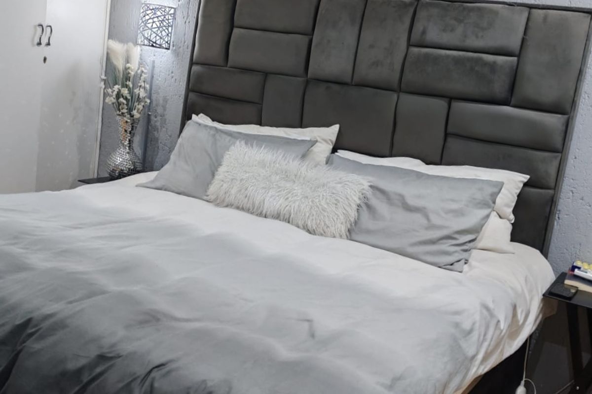 A well-maintained bedroom featuring laminate flooring, a textured feature wall, and a built-in wardrobe.