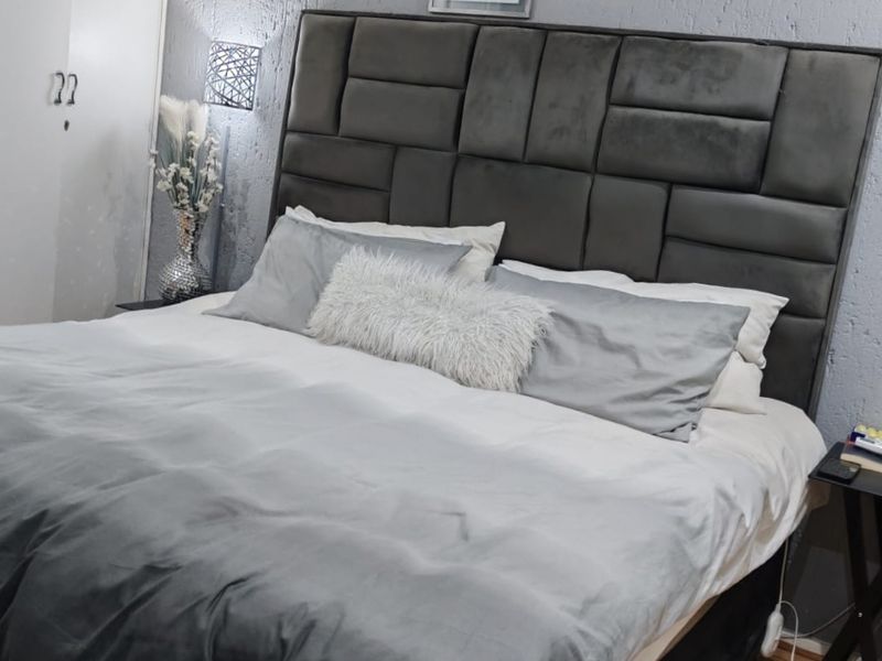 A well-maintained bedroom featuring laminate flooring, a textured feature wall, and a built-in wardrobe.