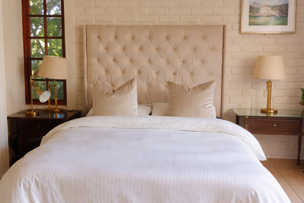 A well-maintained bedroom featuring a textured exposed brick feature wall, neutral tiled flooring, and a classic timber-framed window.