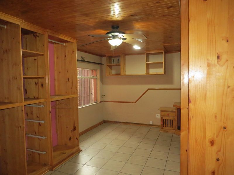 A bedroom featuring built-in wooden cabinetry, tiled flooring, and a wooden ceiling with an integrated fan.