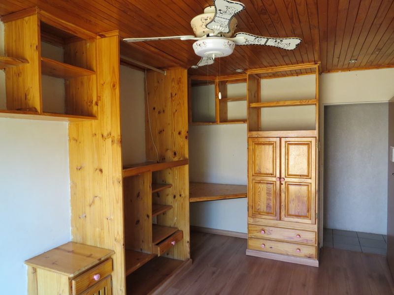 Bedroom featuring extensive built-in pine cabinetry, a dedicated desk area, timber ceiling with fan, and laminate flooring.