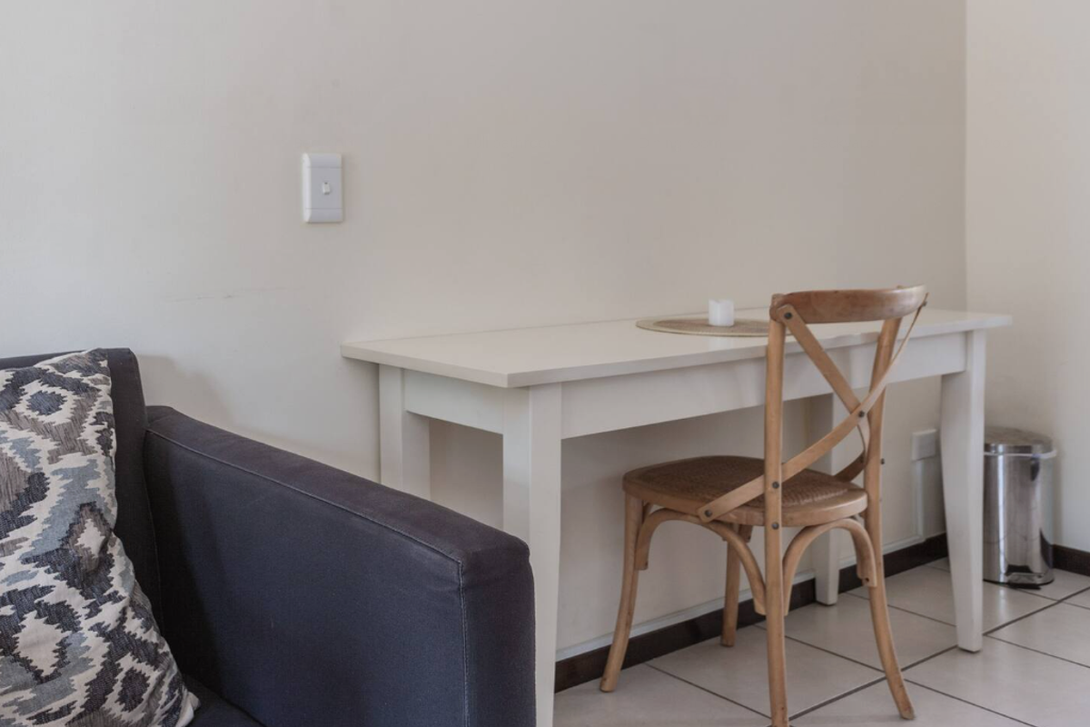 A functional living area featuring neutral wall finishes and tiled flooring, suitable for a compact workspace or dining setup.