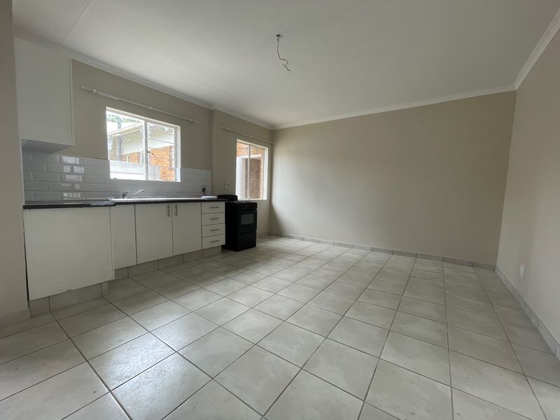 A clean, empty kitchen featuring white cabinetry, a subway tile backsplash, black countertops, and ceramic floor tiles, ready for personalization.