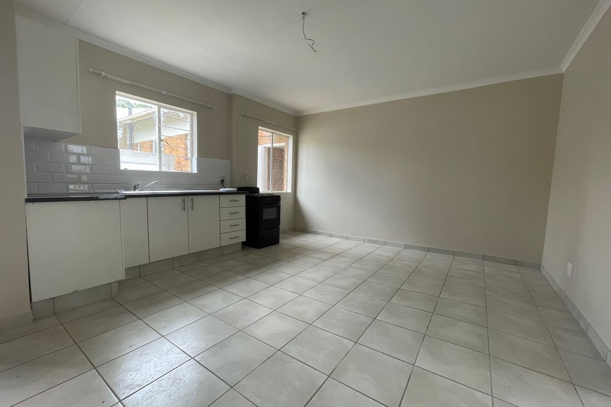 A clean, empty kitchen featuring white cabinetry, a subway tile backsplash, black countertops, and ceramic floor tiles, ready for personalization.