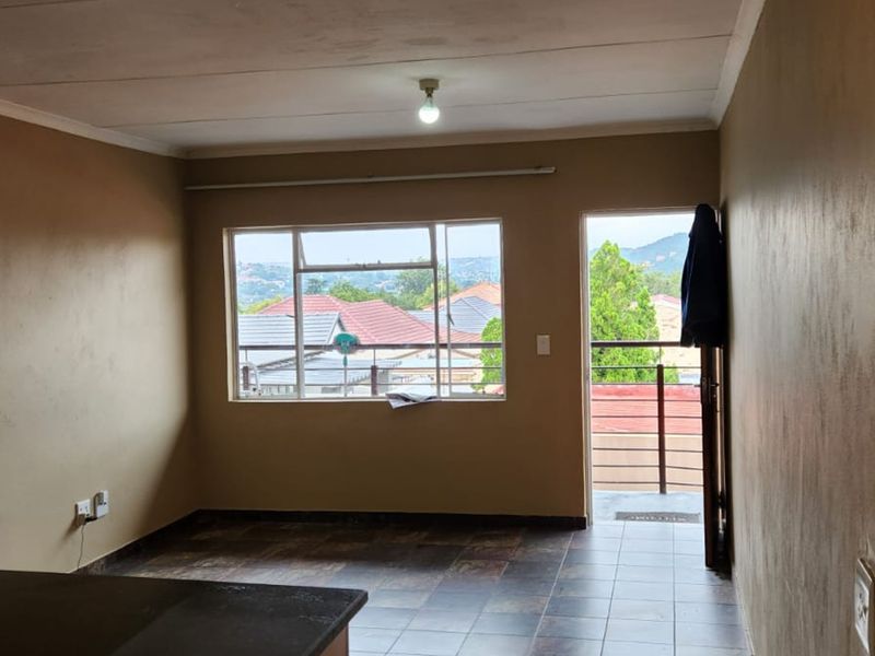 An empty living area featuring tiled flooring, built-in shelving, and direct access to a balcony with neighborhood views.
