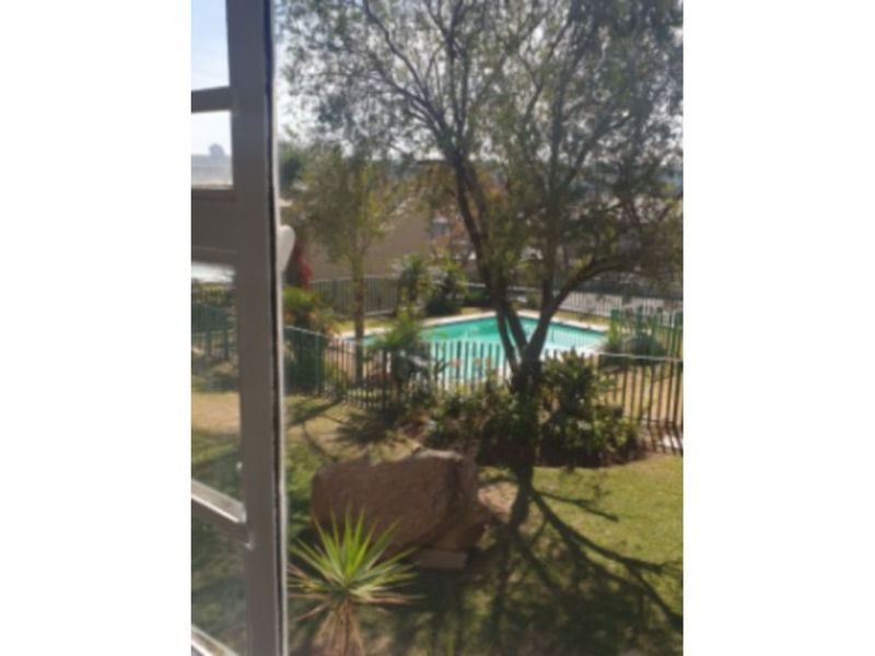 View of a private swimming pool area with metal perimeter fencing and established garden landscaping, captured from an elevated vantage point.