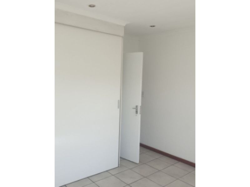 An empty bedroom featuring tiled flooring, built-in wardrobe storage, and recessed ceiling lighting.