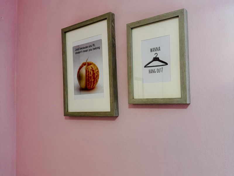 A close-up view of a pink painted wall featuring two framed decorative prints.