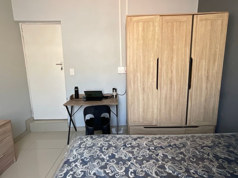 A functional bedroom featuring tiled flooring and a built-in wardrobe, providing practical storage space within the room.