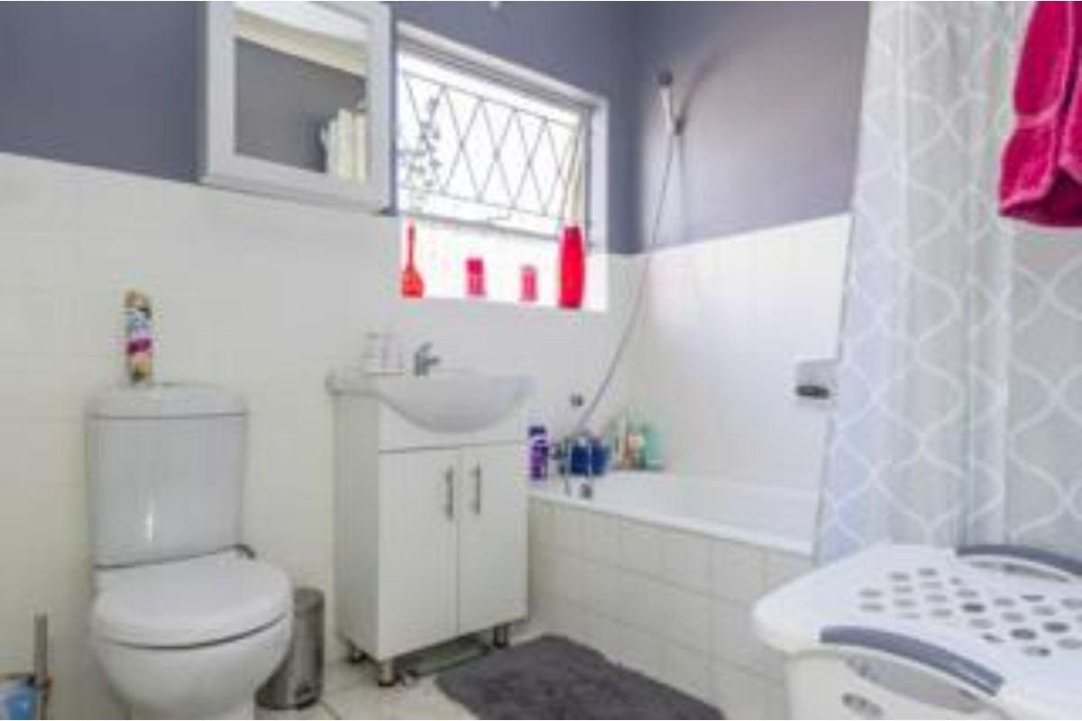 A functional bathroom featuring a white vanity basin, toilet, and a bathtub with a shower attachment, finished with tiled splashbacks.