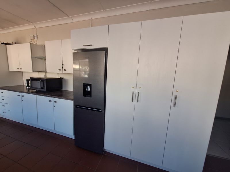 A functional kitchen featuring white built-in cabinetry, dark laminate countertops, and a modern stainless steel refrigerator.
