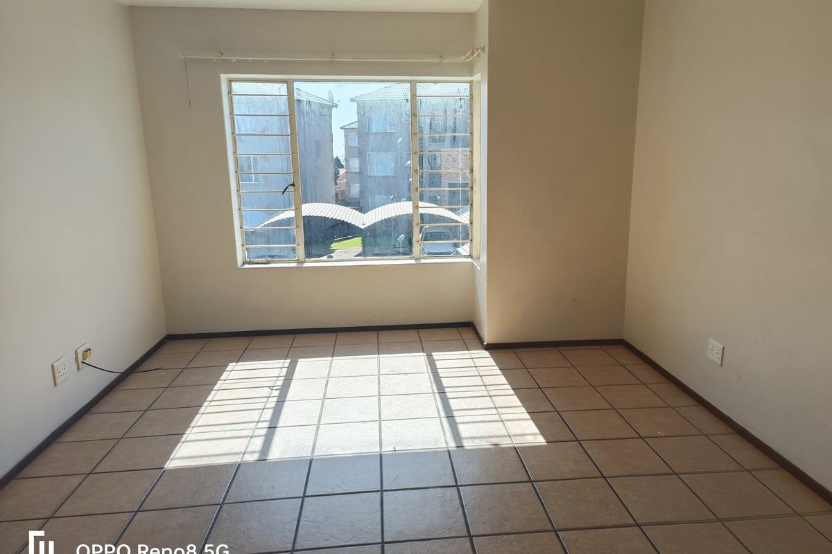 An empty bedroom featuring tiled flooring and metal security bars on the window, providing a blank canvas for personalization.