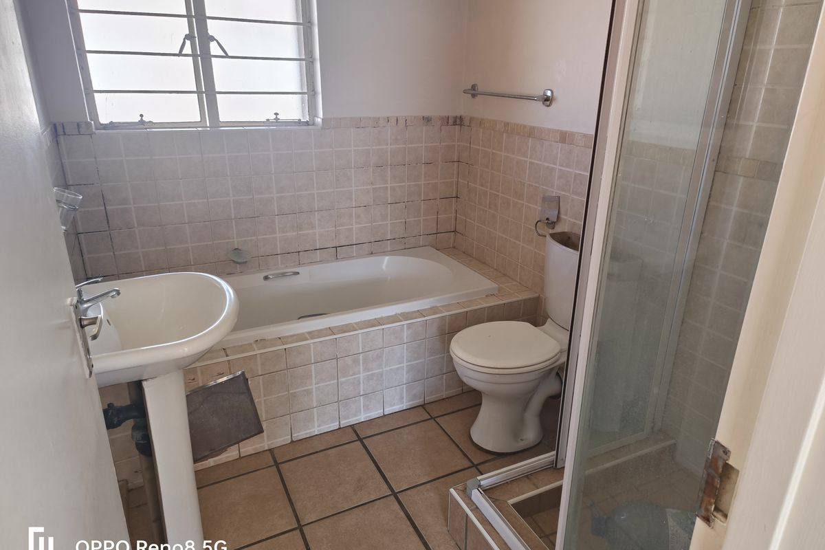 A dated bathroom featuring a pedestal basin, built-in bathtub, and separate shower enclosure with ceramic tiling throughout.